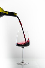 A glass with splashes of red wine on a gray background. The wine spilled from the glass.