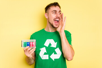 Young man holding batteries to recycle them cut out isolated shouting and holding palm near opened...