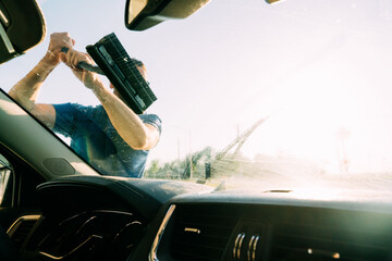 Scrubbing a car window clean of dirt. 