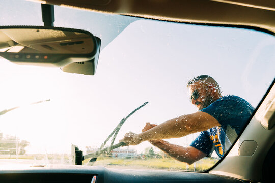 A Guy Cleaning A Windshield At A Car Wash. 