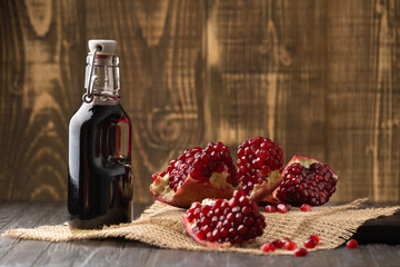 Pomegranate, scattered seeds and pomegranate juice on a wooden background .