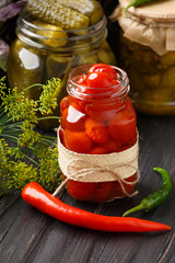 Jars with canned tomatoes and cucumbers on wooden background