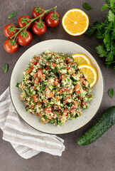 Tabbouleh salad with quinoa, tomatoes, cucumbers, parsley, mint and lemon juice on a white wooden background. Top view. Traditional Middle Eastern and Levantine cuisine.