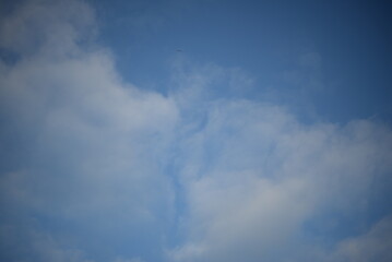 Fototapeta premium rays of the sun through the cirrus clouds against the blue sky, white rainy clouds blue sky illuminated by the rays of the sun, one small cirrus cloud blurred clouds background