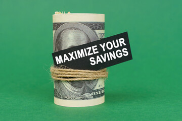 On a green surface, rolled dollars with a black sign that says - Maximize your savings