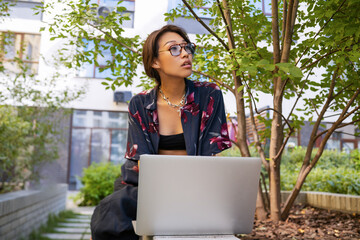 Asian student using devices in a green garden