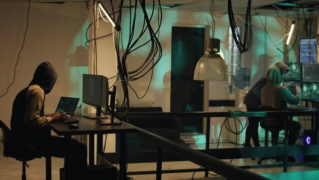 Male skilled hacker using knowledge of computer systems to access sensitive information, breaking into a computer system. Thief using trojan virus to create computer malware. Tripod shot.