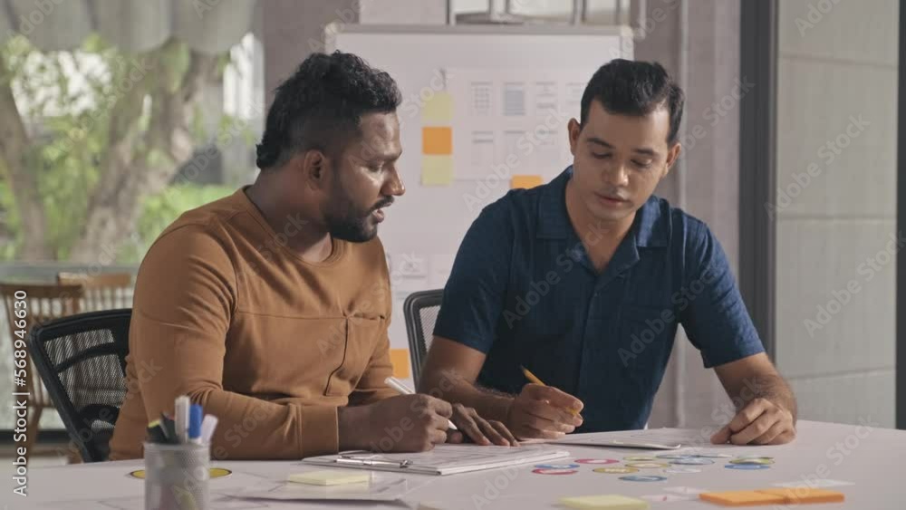 Canvas Prints medium shot of two indian coworkers discussing sketches while developing it project in office