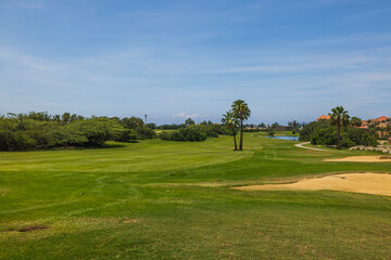 Fototapeta na wymiar Gorgeous view of green grass golf field on background blue sky on Aruba island. 