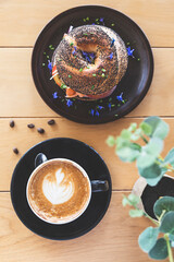 Coffee prepared by a barista in a black cup on a restaurant table. Food accompanying the coffee. Breakfast. Beginning of the day.