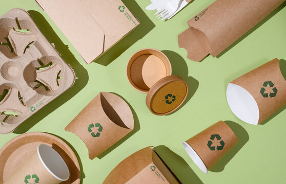 Disposable eco-friendly packaging with a recycling sign on a green background. Reusable raw materials.