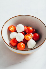 Preparation for Classic italian salad caprese served in original form with cherry tomatoes and mini mozarella pearls