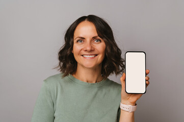 Close up portrait of a wide smiling woman showing the screen of the phone.