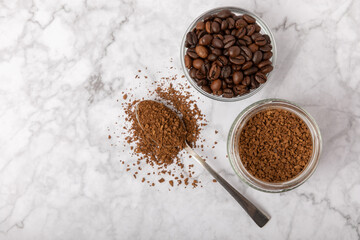Coffee granules and coffee beans on a white marble background. Instant coffee drink. Energy hot...
