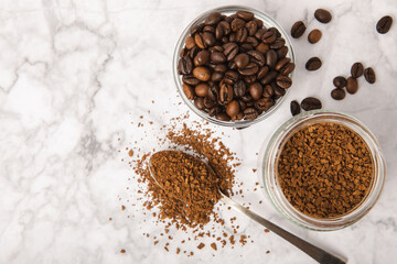 Coffee granules and coffee beans on a white marble background. Instant coffee drink. Energy hot...