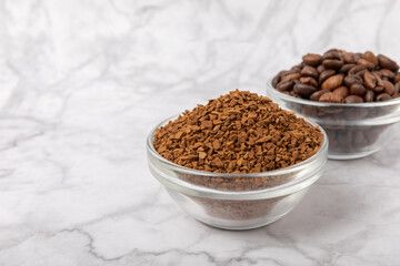 Coffee granules and coffee beans on a white marble background. Instant coffee drink. Energy hot...