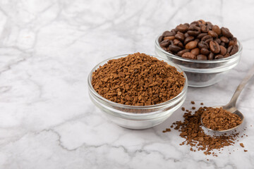 Coffee granules and coffee beans on a white marble background. Instant coffee drink. Energy hot...
