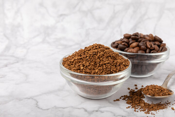 Coffee granules and coffee beans on a white marble background. Instant coffee drink. Energy hot...