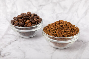 Coffee granules and coffee beans on a white marble background. Instant coffee drink. Energy hot...