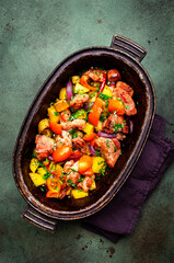 Turkey drumsticks roast with potatoes, paprika, onions, herbs and spices in rustic cast iron pan, old green table background, top view