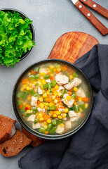 Hot vegetable soup with chicken, corn and green beans. Comfort food. Gray table background, top view