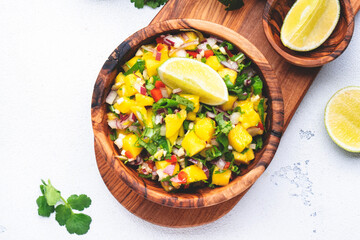 Spicy mango salsa sauce with red chili peppers, onion, garlic, lime and cilantro, white table background, top view