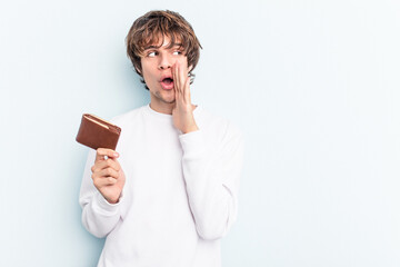 Young caucasian man holding a ballet isolated on blue background is saying a secret hot braking news and looking aside