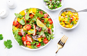 Fresh salad with grilled chicken slice with mango salsa, tomato, cilantro, red onion and lettuce in mexican style, white table background, top view