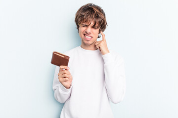 Young caucasian man holding a ballet isolated on blue background covering ears with hands.
