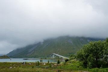 Beautiful nature landscape in North. Scenic outdoors view. Ocean with waves and mountains. Big dark stones. Dramatic storm clouds. Extreme weather, rain and wind. Explore Norway, summer adventure