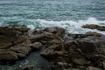 Rocky shore with black big stone on the island