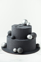 Anniversary luxury black bunk cake with chocolate velvet coating isolated on white background. Birthday cake with black velvet texture decorated with silver chocolate spheres