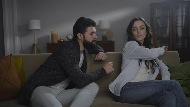 Young resentful woman pushes her husband away and asks not to touch her. A young couple in a quarrel