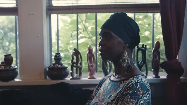 Black Stock Footage of happy, successful, and knowledgeable elderly Black African senior woman in her afro-centric library filled with African books as she reads and learns