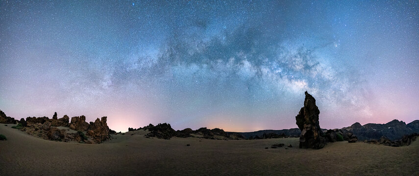 Milky way galaxy arch panorama over rock formations.