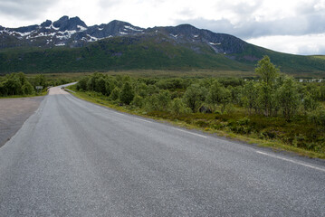 Scenic road along the fjords in Norway. Amazing landscape. Northern nature. Snow-capped mountains. Dramatic clouds. Travel, adventure
