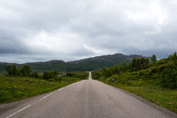 Scenic road along the fjords in Norway. Amazing landscape. Northern nature. Snow-capped mountains. Dramatic clouds. Travel, adventure