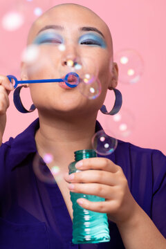 Stylish Gen Z woman blowing bubbles in colorful studio setting