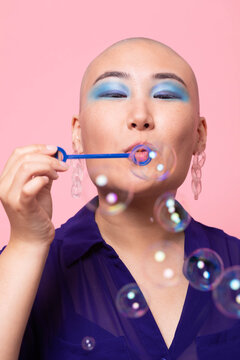 Stylish Gen Z woman blowing bubbles in colorful studio setting
