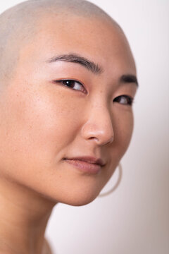 Portrait of bald Asian woman against white