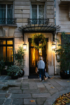 Teenage girl entering a beautiful Parisian building with shopping. 