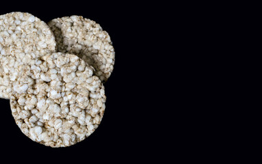 Three round rice crackers on a black background close-up. Crispy rice diet product for a healthy lifestyle. Top view puffed rice cakes on a black isolated background. Free space for text