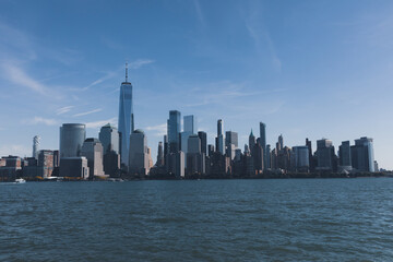 Hudson river harbor with Manhattan skyscrapers in New York City under blue sky.