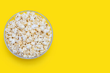 Popcorn in a large glass bowl on a yellow background, top view. Crispy classic popcorn snack for watching movies and series. Delicious light snack for watching TV. Free space for text
