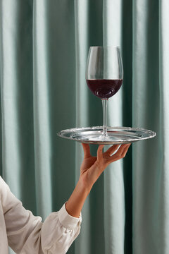 Crop waiter with wineglass on tray