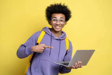 Young happy African American man freelancer using laptop computer, pointing index finger on laptop...