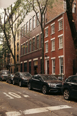 Fototapeta na wymiar Cars and brick houses on street in New York City.