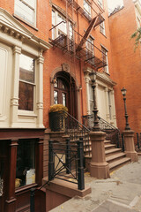 Fototapeta na wymiar brick house with stairs and white stucco decor on urban street in New York City.