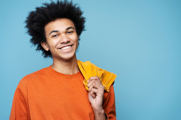 Closeup portrait of smiling African American man wearing stylish clothes isolated on blue background, copy space. Happy smart student with curly hair looking at camera posing for pictures, studio shot