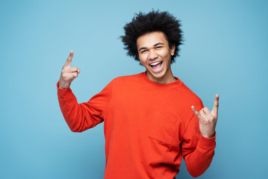 Young Emotional African American Man Screaming, Showing Rock Sign Isolated On Blue Background  